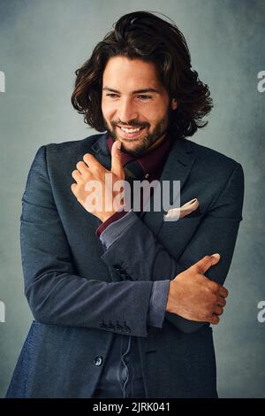 HES un dude décontracté avec style. Photo studio d'un jeune homme élégant et habillé debout avec sa main sur son menton. Banque D'Images