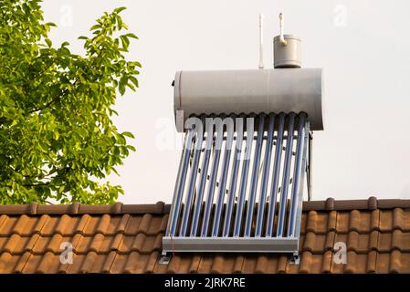 chauffage thermique de panneau solaire en acier inoxydable chaudière chauffage eau toit d'une maison arbre vert vide collecteurs d'air tuiles de toit en argile Banque D'Images