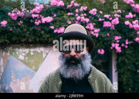 Le portrait d'un homme caucasien à barbe fantaisie portant un chapeau et des lunettes de soleil à la mode Banque D'Images