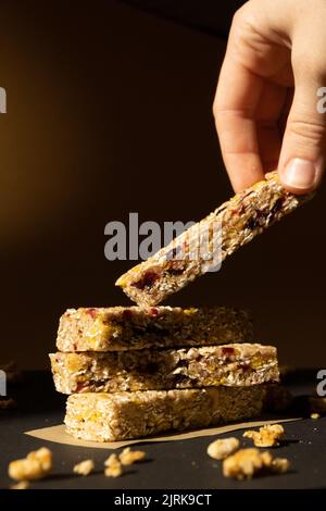 Femme prend le bar énergétique Granola naturel maison. Variété de barres de petit-déjeuner de granola de protéines, avec noix, raisins secs, cerises séchées et chocolat. Nutrition saine alimentation. Collation sans gluten aux céréales Super food Sport Oridge bar Vega dessert concept Banque D'Images