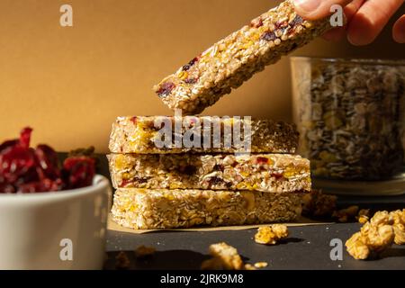 Femme prend le bar énergétique Granola naturel maison. Variété de barres de petit-déjeuner de granola de protéines, avec noix, raisins secs, cerises séchées et chocolat. Nutrition saine alimentation. Collation sans gluten aux céréales Super food Sport Oridge bar Vega dessert concept Banque D'Images