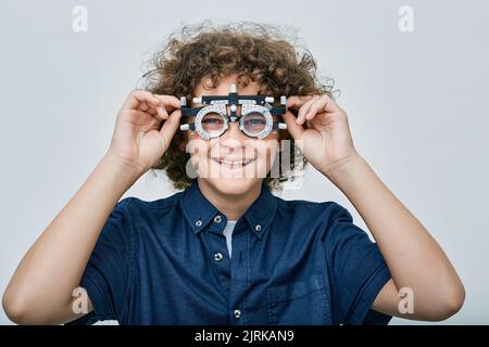 Jeune garçon portant un cadre d'essai optométriste avec lentille à la clinique d'ophtalmologie. Sélection de lunettes dioptries pour le traitement de la vision des enfants Banque D'Images