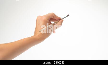 La main gauche d'une femme tient un pinceau pour dessiner sur un fond blanc Banque D'Images