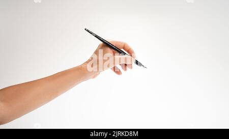 La main gauche d'une femme tient un stylo pour écrire un geste de calligraphie. Photo de haute qualité Banque D'Images