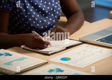 Image rognée d'une femme d'affaires prenant des notes dans son planificateur Banque D'Images