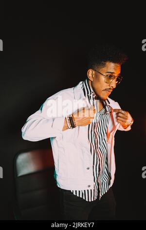 Jeune homme masculin afro-américain portant des vêtements élégants et des lunettes de soleil avec bracelets veste réglable Banque D'Images