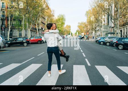 Ravi homme tournant autour de la femme souriante tout en s'amusant sur les passages en ville Banque D'Images