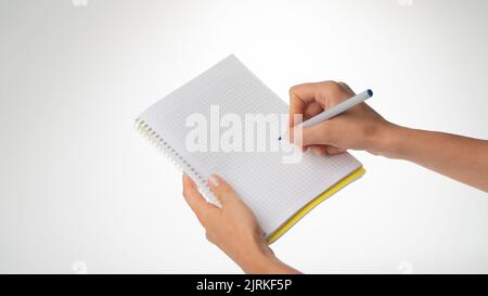 Les mains des femmes tiennent un ordinateur portable, un stylo dans sa main droite écrit dans un ordinateur portable dans une cage. Photo de haute qualité Banque D'Images