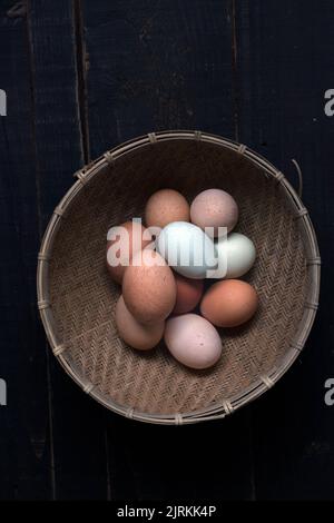 De la photo ci-dessus du panier en osier rempli d'œufs bruns et blancs sur la table Banque D'Images