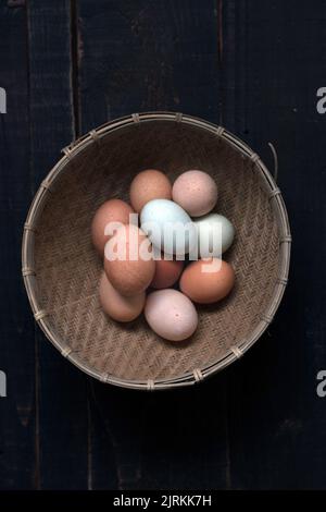 De la photo ci-dessus du panier en osier rempli d'œufs bruns et blancs sur la table Banque D'Images