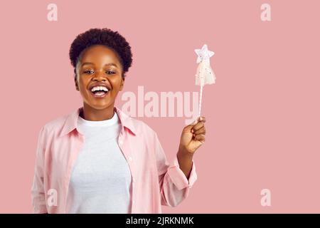 Portrait de bonne drôle souriante jeune femme avec baguette magique sur fond rose studio Banque D'Images