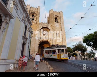 Cathédrale Saint Mary Major alias Cathédrale de Lisbonne alias Sé de Lisboa. Un tramway passe devant la cathédrale tandis que les touristes se promèdonnent dans la rue. Banque D'Images