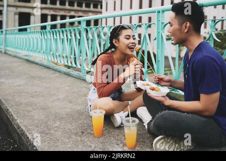 Couple asiatique assis sur le trottoir et manger de la nourriture de rue Banque D'Images