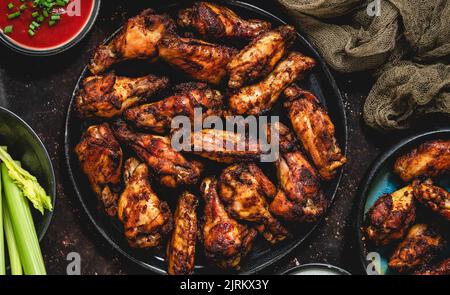 Ailes de poulet épicées grillées servies avec sauce tomate et yaourt, céleri et carottes Banque D'Images
