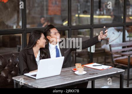 couple d'affaires prenant une photo d'elle-même à l'aide d'un smartphone Banque D'Images