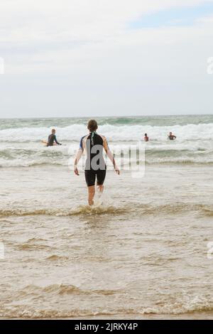 Femme en combinaison qui s'est délasée de l'arrière, Woolacombe, North Devon, Angleterre, Royaume-Uni Banque D'Images