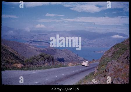 Port de Lyttelton depuis Dyer's Pass montrant Quail ID, péninsule de Moeputu (entre la tête de la baie et la baie de Charteris), avec route vers Rapaki, 24 mars 1959-13 April1959, Canterbury, par Leslie Adkin. Don de la famille Adkin, 1997. Banque D'Images