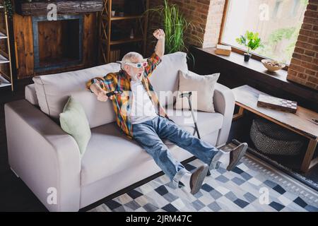 Photo de l'homme à la retraite, chanceux, vêtu d'une chemise à carreaux 3D verres regardant un film assis canapé à l'intérieur de l'appartement Banque D'Images