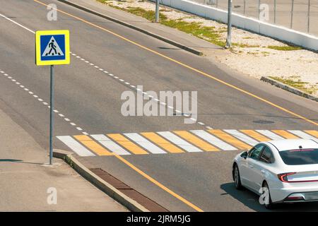 Passage pour piétons avec un panneau routier traversant la route de la ville, la voiture blanche s'est arrêtée avant que le passage ne cède aux piétons Banque D'Images