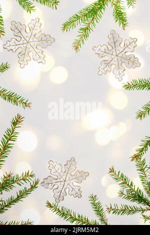 Cadre de Noël en branches de sapin vert, flocons de neige décoratifs sur fond gris neutre avec lumières de Noël dorées. Vacances d'hiver, nouvel an. Chris Banque D'Images