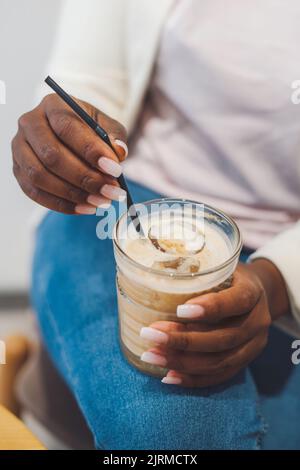 Portrait en gros plan des mains de la femme tenant un verre de café glacé avec des glaçons. Délicieux café glacé. Boissons d'été Banque D'Images