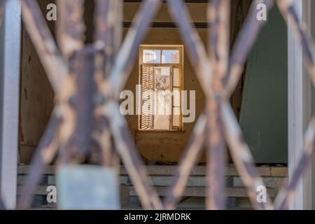 Une fenêtre endommagée, un foyer sélectif endommagé une fenêtre ouverte en bois derrière la rambarde dans une ville abandonnée, Varosha à Famagousta, au nord de Chypre Banque D'Images