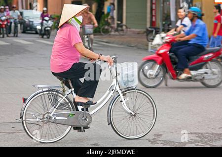 Femme vietnamienne portant un chapeau de bambou sur un vélo, Hai Phong, Vietnam Banque D'Images