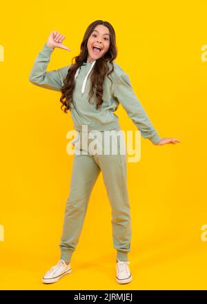 Une jeune fille surprise. Adorable jeune fille dans un pull à capuche et un pantalon de sport décontracté violet et des baskets blanches posé sur fond blanc. Maquette pour impression Banque D'Images