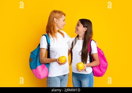 Concept d'école, d'apprentissage et d'éducation. Mère et fille écolières avec sac à dos d'école et pomme prêt à apprendre Banque D'Images