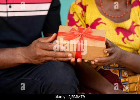 un jeune homme africain donne un cadeau à une vieille femme africaine Banque D'Images