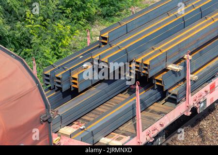 Tas de tas épais brut rouillé poutres en fer chargé sur le transport de fret ferroviaire. L'usine de produits métalliques usine de produits d'expédition et Banque D'Images