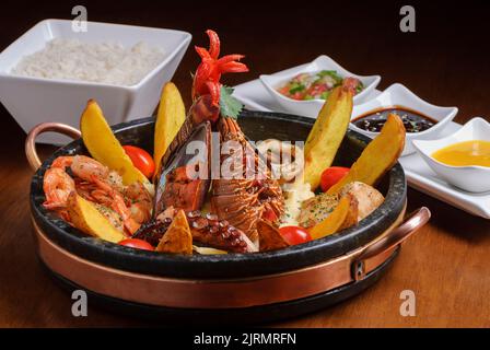 Plat avec fruits de mer, pieuvre, moules, crevettes, homard et calmar, accompagné de pommes de terre, de riz et de sauces. Banque D'Images