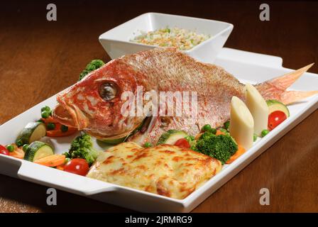 Poisson frit avec légumes sur une table en bois. Banque D'Images