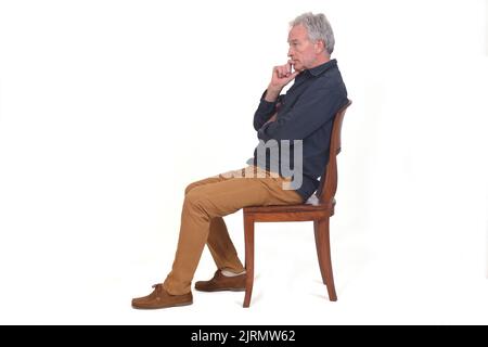 vue latérale d'un pensif assis sur une chaise sur fond blanc Banque D'Images