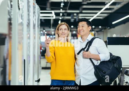 Joyeux couple asiatique homme et femme de famille faire un choix de nouveaux appareils ménagers à la maison dans le supermarché enquête réfrigérateur réfrigérateur, congélateur, l'achat de chambre froide et les achats Banque D'Images