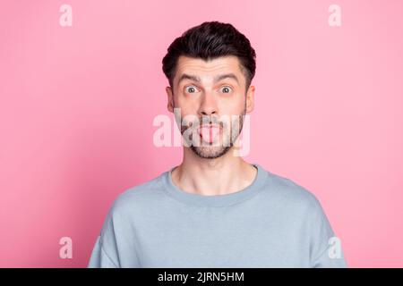 Portrait d'un jeune homme positif montrant la langue dehors regarder l'appareil photo isolé sur fond rose pastel Banque D'Images