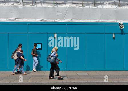 Les gens passant par un bâtiment bleu de palissade créant une image abstraite, sur Oxford Street Angleterre de Londres Banque D'Images