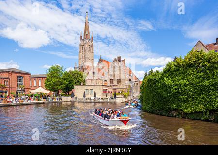 La flèche de l'église notre-Dame (onze-Lieve-Vrouwekerk) surplombant l'hôpital St Johns (Sint-Janshospitaal) et les touristes profitant d'une excursion en bateau le Th Banque D'Images