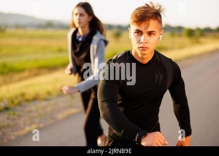 Vous avez la possibilité d'aller plus haut. Photo d'un couple sportif qui court sur une route de montagne. Banque D'Images