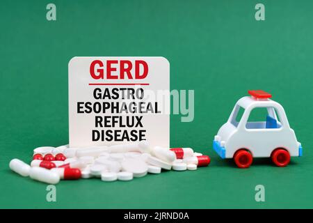 Concept médical. Sur une surface verte, une ambulance, des pilules et un signe blanc avec l'inscription - maladie de reflux gastro-oesophagien Banque D'Images