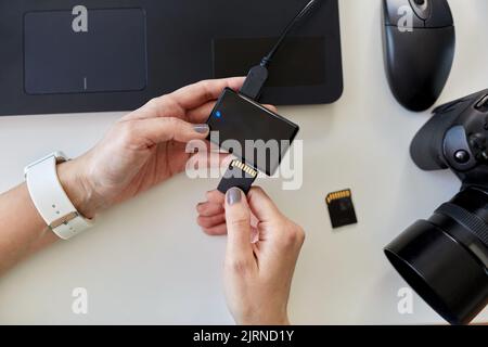 mains avec lecteur de carte sd, ordinateur portable et appareil photo Banque D'Images