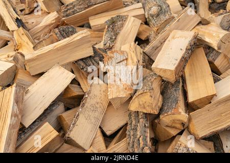 Bois de chauffage sec scié et haché dans une pile sous le ciel ouvert. Arrière-plan vintage créatif. Banque D'Images