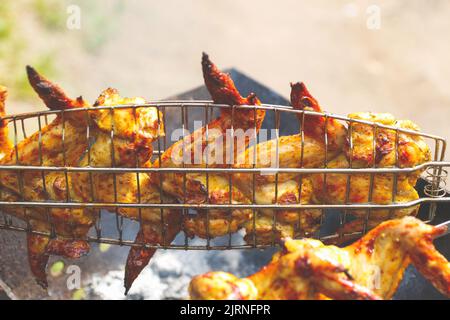 Recentrer de délicieuses ailes de poulet sur le gril chaud. Les cuisses et les ailes de poulet sont frites sur des coals dans un brazier dans un barbecue, poulet mariné i Banque D'Images