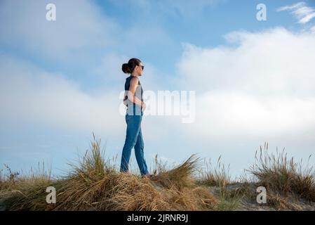 Jeune femme portant des jeans et marchant pieds nus à travers les dunes de sable Banque D'Images