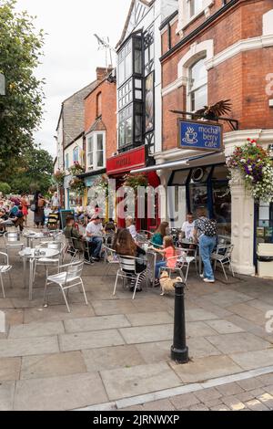 Les gens se sont assis dans les cafés de la rue dans le centre-ville de Glastonbury, place du marché, Glastonbury, Somerset, Angleterre, ROYAUME-UNI Banque D'Images