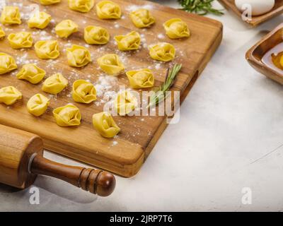 Des boulettes crues faites maison sur une planche à découper en bois attendent d'être cuites. Isolé sur fond blanc. Il n'y a aucune personne dans la photo. Il y a fr Banque D'Images