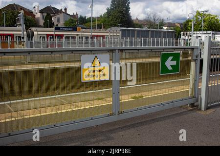 Gare de Wimbledon, sud-ouest de Londres, Royaume-Uni ; un panneau sur la clôture séparant les plates-formes avertissant contre la porte coulissante Banque D'Images