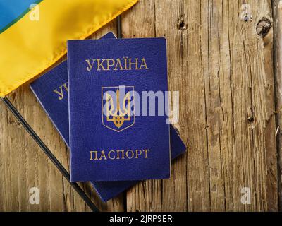 Sur une simple table en bois se trouvent deux passeports biométriques des citoyens de l'Ukraine et un petit drapeau ukrainien jaune-bleu. Voyage à l'étranger, tourisme, émigration Banque D'Images