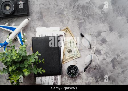 Tourisme et repos. Attributs pour un voyage, un voyage - une boussole, un appareil photo, des billets, de l'argent, un passeport, lunettes, un avion jouet. Isolé sur un fond gris Banque D'Images