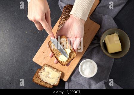 boulanger femelle répartissant le beurre sur du pain fait maison Banque D'Images